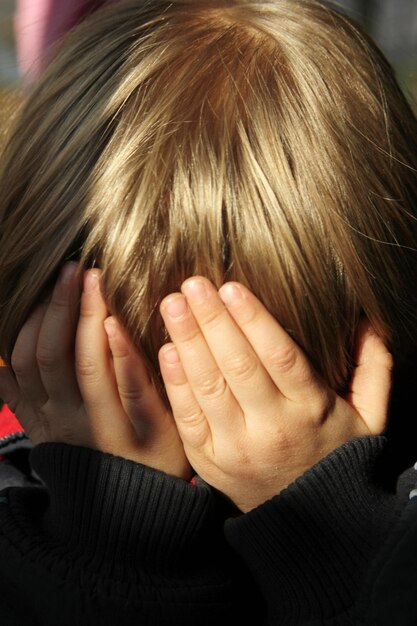 Jongen met blond haar dat zijn gezicht bedekt