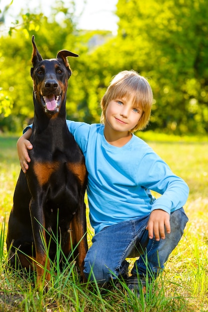 Foto jongen met dobermann in zomerpark.