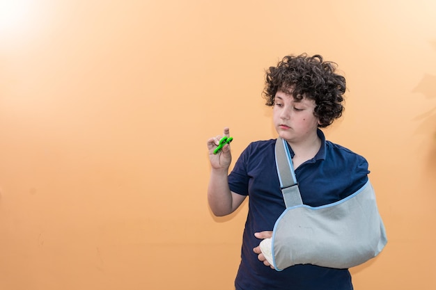 Foto jongen met een gebroken hand die tegen de muur speelt.