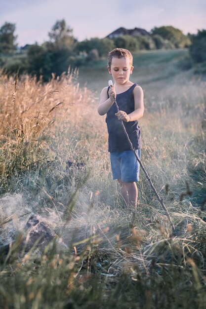 Foto jongen met een marshmallow met een stok terwijl hij op het veld staat