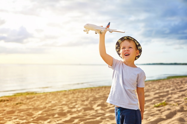 Jongen met een vliegtuig in zijn handen op het strand