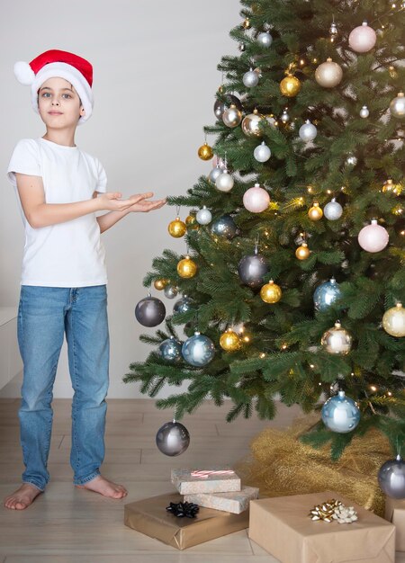 Jongen met geschenken speelt in de buurt van de kerstboom. Woonkamer interieur met kerstboom en versieringen. Nieuwjaar. Cadeaus geven.