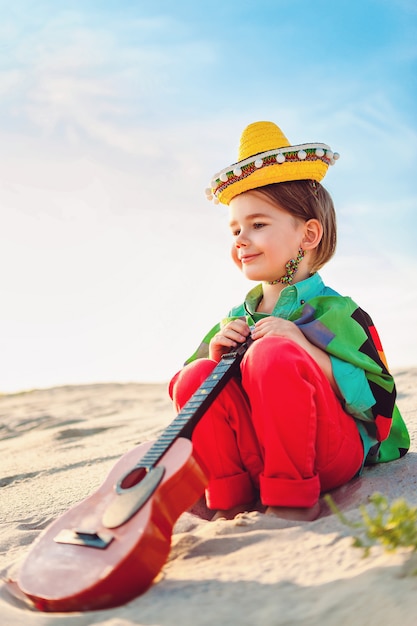 Jongen met gitaar zittend op zand