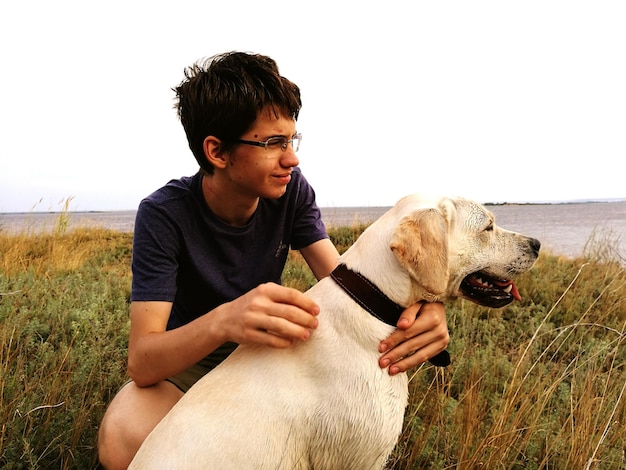 Jongen met hond op het veld tegen een heldere lucht