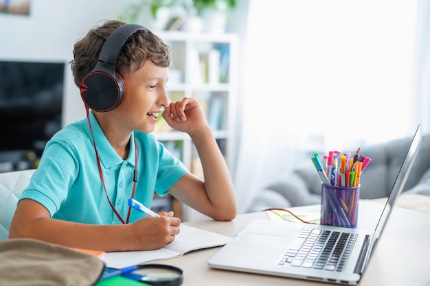 Jongen met koptelefoon met laptop voor huiswerk