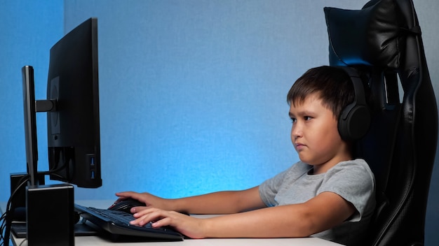 Jongen met koptelefoon spelen op de computer, close-up