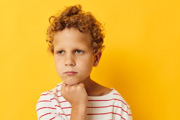 Jongen met krullend haar op een gestreepte t-shirt gele achtergrond