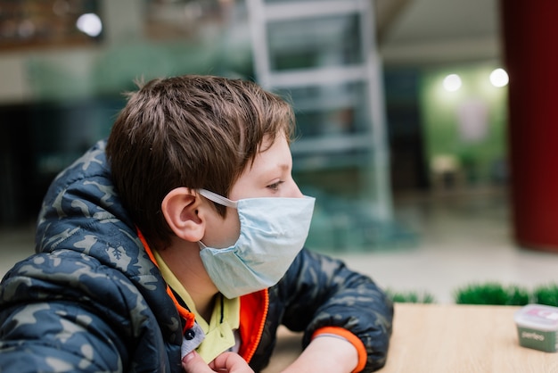 Jongen met medisch gezichtsmasker, beschermende maatregelen tegen verspreiding van Covid-19