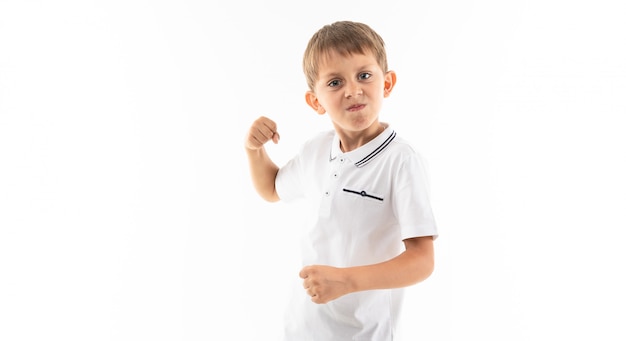 Jongen met pony in een wit t-shirt met vuisten op wit met kopie ruimte