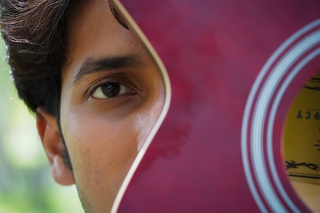 Foto jongen met rode gitaar close-up ogen