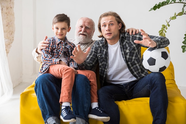 Jongen met vader en grootvader voetbal kijken thuis