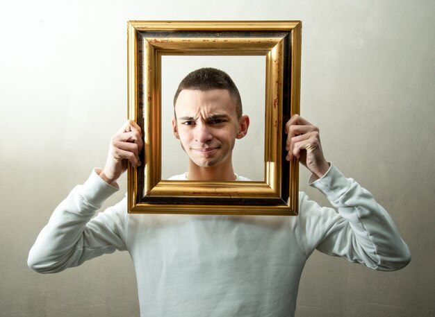 Jongen met vreemde uitdrukking met een frame om zijn gezicht