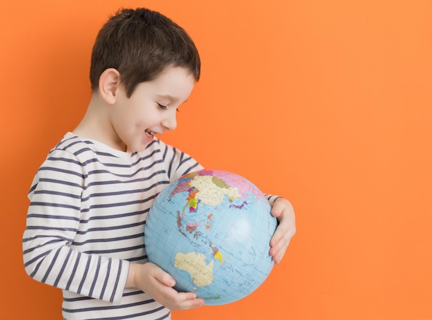 Jongen met wereldbol op oranje achtergrond