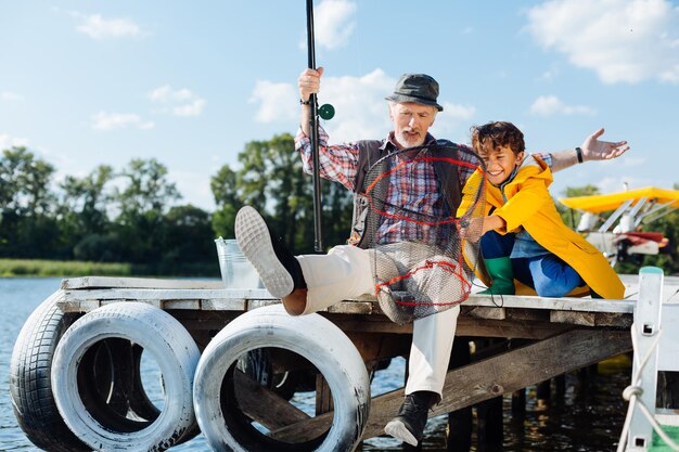 Jongen na het vangen van vis in het net met opa