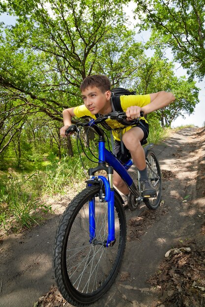 Jongen op een fiets die door het bos reist