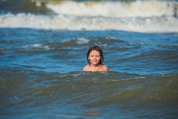 Jongen op strand tijdens zomervakantie Kind zwemmen in zee met wawes