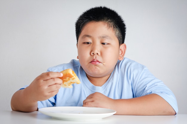 jongen pizza eten aan tafel