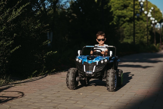 jongen rijdt in de zomer in een mini-speelgoedauto in het park