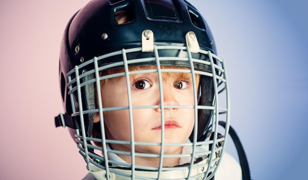 Jongen schattig kind draagt hockeyhelm close-up veiligheid en bescherming beschermend raster op gezicht sportuitrusting...