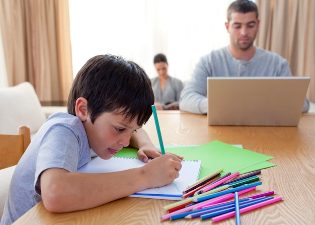 Jongen schilderen en ouders thuis werken