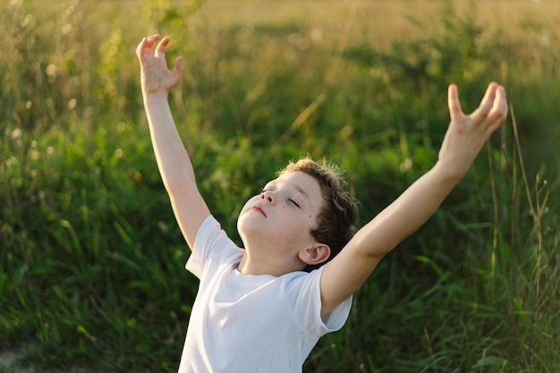 Jongen sloot haar ogen en bad in een veld bij zonsondergang Handen gevouwen in gebedsconcept voor geloofsspiritualiteit en religie