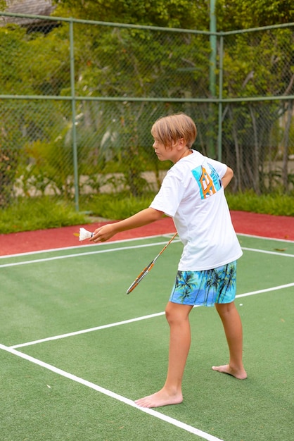 jongen speelt badminton buiten in de frisse lucht gooit een shuttlecock en houdt een racket een eiland in de Malediven actieve recreatie en sport.