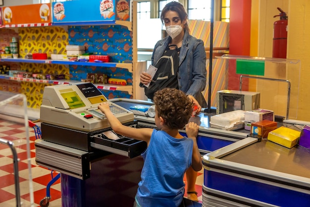 Jongen speelt een supermarktkassier met zijn moeder