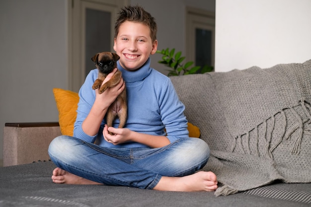 Foto jongen speelt met babyhond. kid spelen met puppy thuis. kleine jongen en griffon of brabanson hond