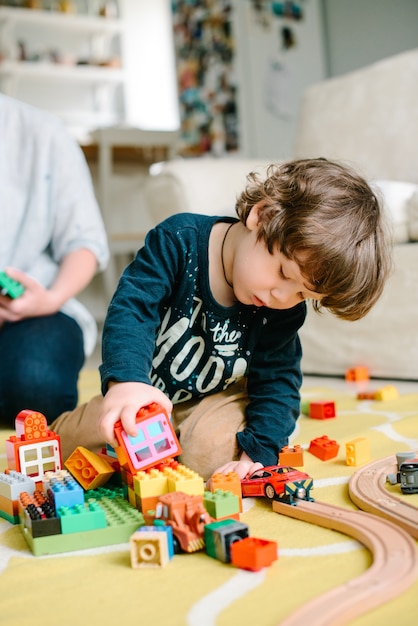 Jongen speelt met bouwstenen thuis op de vloer