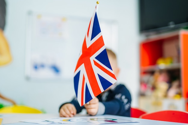 Jongen speelt met britse vlag. kind houdt de vlag van groot-brittannië vast. engelse vlag in de handen van het meisje.