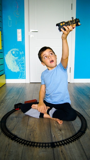 Jongen speelt met de trein. Kind speelt met treinstation op de vloer in de kinderkamer.