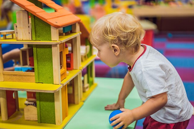 Jongen speelt met een houten huis van houten kubussen