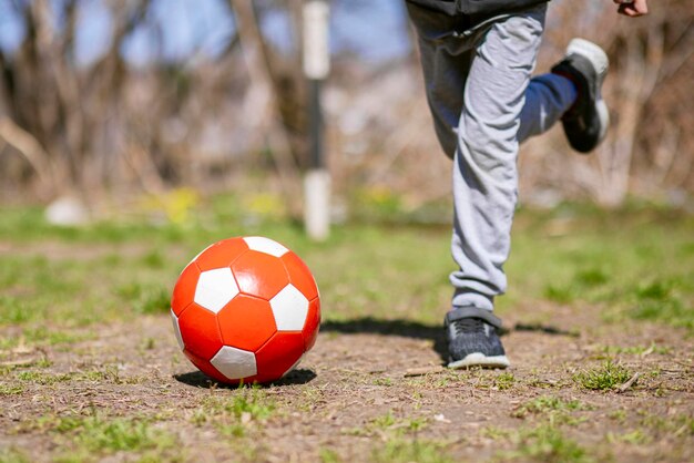 Jongen speelt met een voetbal op het voetbalveld in het park Kinderactiviteiten