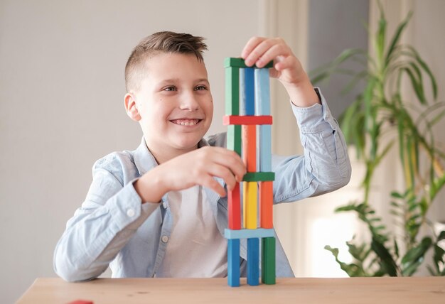 Jongen speelt met gekleurde houten stenen door toren te bouwen Motorische vaardigheden verbeteren Spel thuis spelen