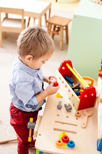 Jongen speelt met houten bouwinstrumenten in de kleuterschool