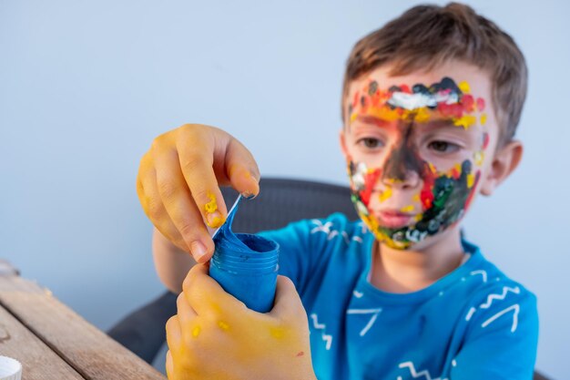 Jongen speelt met kleuren met zijn handen en zijn gezicht
