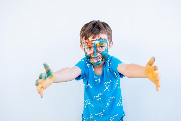 Jongen speelt met kleuren met zijn handen en zijn gezicht