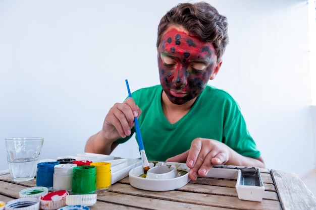 Jongen speelt met kleuren met zijn handen en zijn gezicht