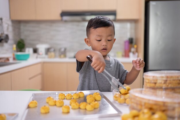 Jongen speelt met nastar cake in de keuken