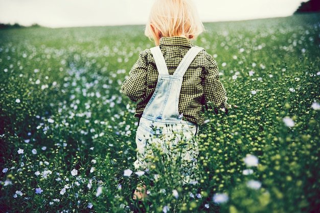 Jongen speelt op een gebied van bloemen