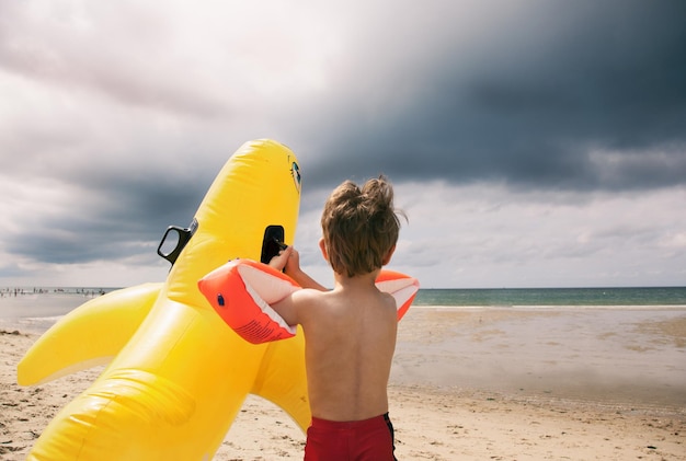 Jongen speelt op het strand tegen bewolkte lucht