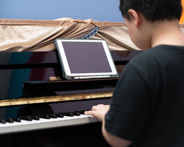 Jongen speelt piano met online leren