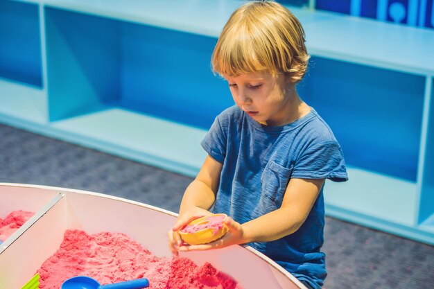 Jongen spelen met kinetisch zand in de kleuterschool. De ontwikkeling van het fijne motorische concept. Creativiteit spelconcept.