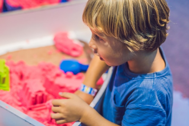 Jongen spelen met kinetisch zand in de kleuterschool. De ontwikkeling van het fijne motorische concept. Creativiteit spelconcept.