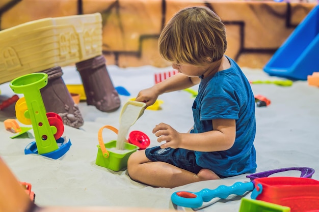 Jongen spelen met zand in de kleuterschool. De ontwikkeling van het fijne motorische concept. Creativiteit spelconcept.