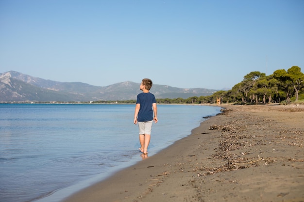 Jongen spelen op het strand op zomervakantie Kinderen in de natuur met prachtig zeezand en blauw rennen in het zeewater