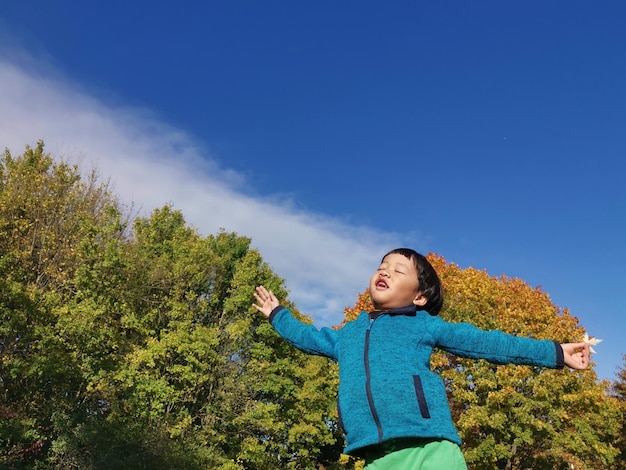 Foto jongen staat bij planten tegen de blauwe lucht