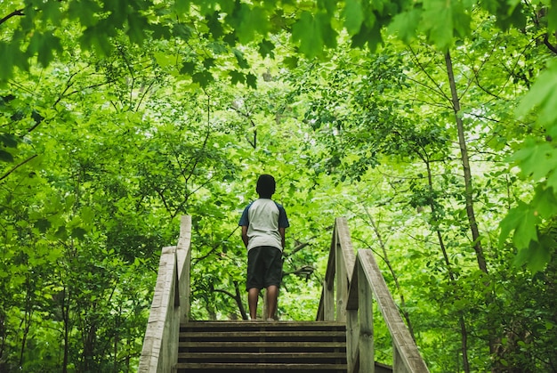 Jongen staat in een jungle met groene bladeren rondom