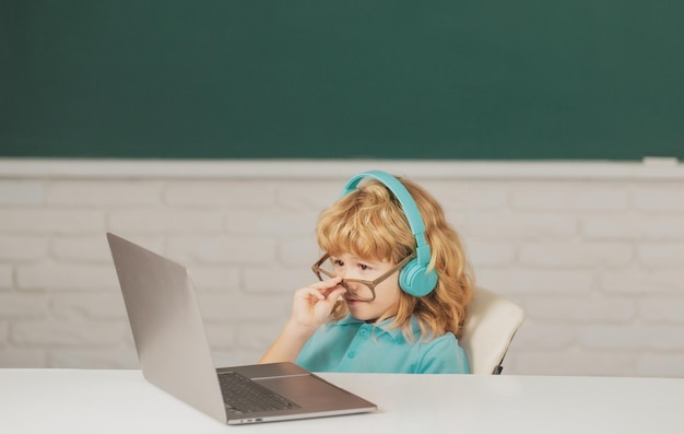 Jongen student leert online in de klas Kind studeert online videogesprek met zoom Leerling kind leert engels online met laptop op school Eerste dag op school
