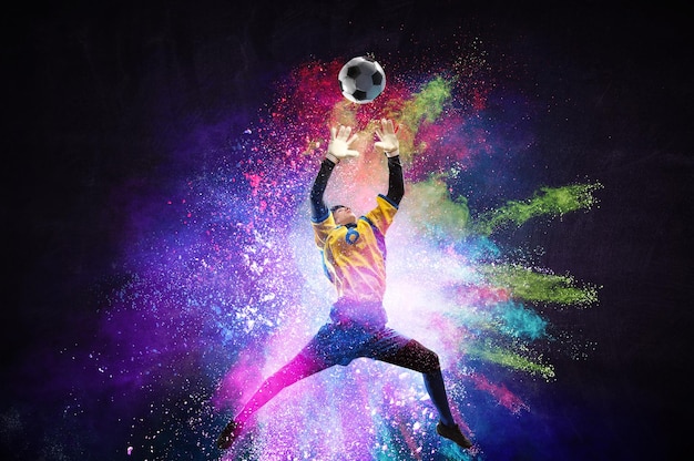 Jongen te voetballen die de bal op kleurrijke achtergrond raakt. Gemengde media